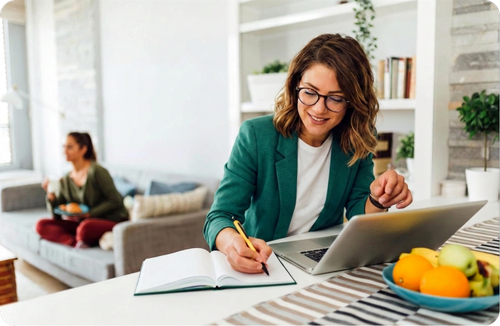 A woman writing in a notebook while working from home
